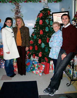 GIVING FAMILY: Chantele Petrocelli, Michele Petrocelli, Claire MacLeod, and Daniel Petrocelli, posed around the giving tree in their preschool. They have collected over 200 gifts that will be donated to the Big Sisters of Rhode Island.