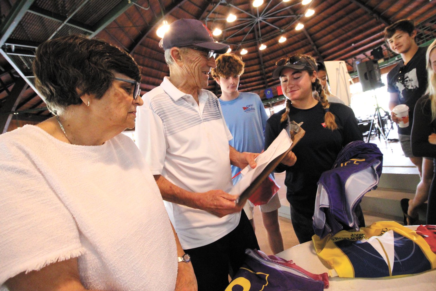 TEAM COLORS: So as to identify competing teams, regatta organizers used color T-shirts from different yacht clubs. Pictured are Cindy and John Cappetta distributing the shirts and registering the teams by color.  (Warwick Beacon photos)
